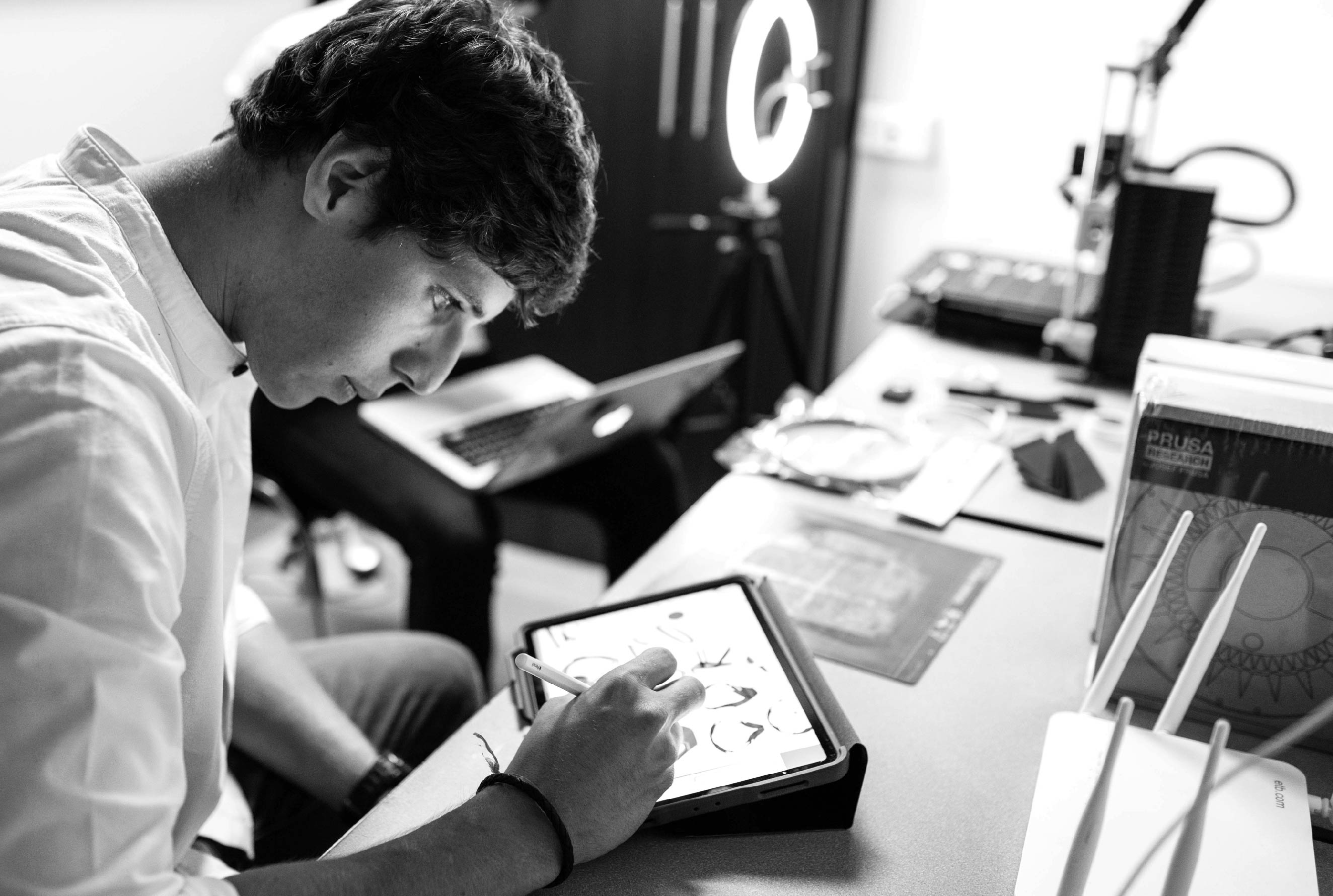 Pablo Llinas sketching on iPad, Prusa printer in background